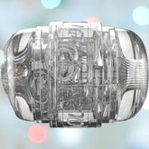 Close-up of a transparent, cylindrical object with intricate internal structures, reminiscent of a Fleshlight Girls Autumn Falls Quickshot Open Ended Male Sex Toy. Set against a soft, blurred background of pastel lights, the Fleshlight toy showcases geometric patterns and a slightly textured end.
